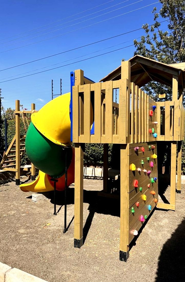 Timber kids' play tower with slide and climbing wall