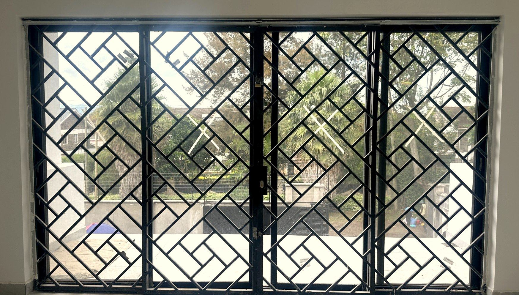 Full-width geometric steel window grills across four sliding panels
